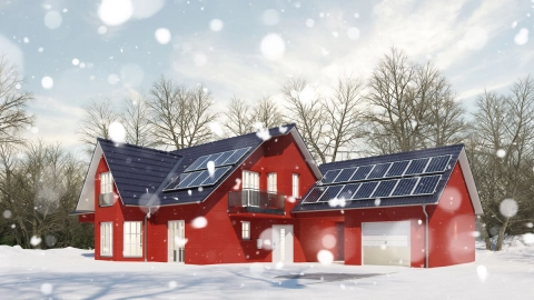 Ein verschneites Haus mit Photovoltaik-Modulen auf dem Dach und Stromspeicher im Keller.